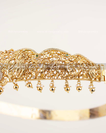 Peacock and forest detailing on gold temple vadanam with CZ and green stones.