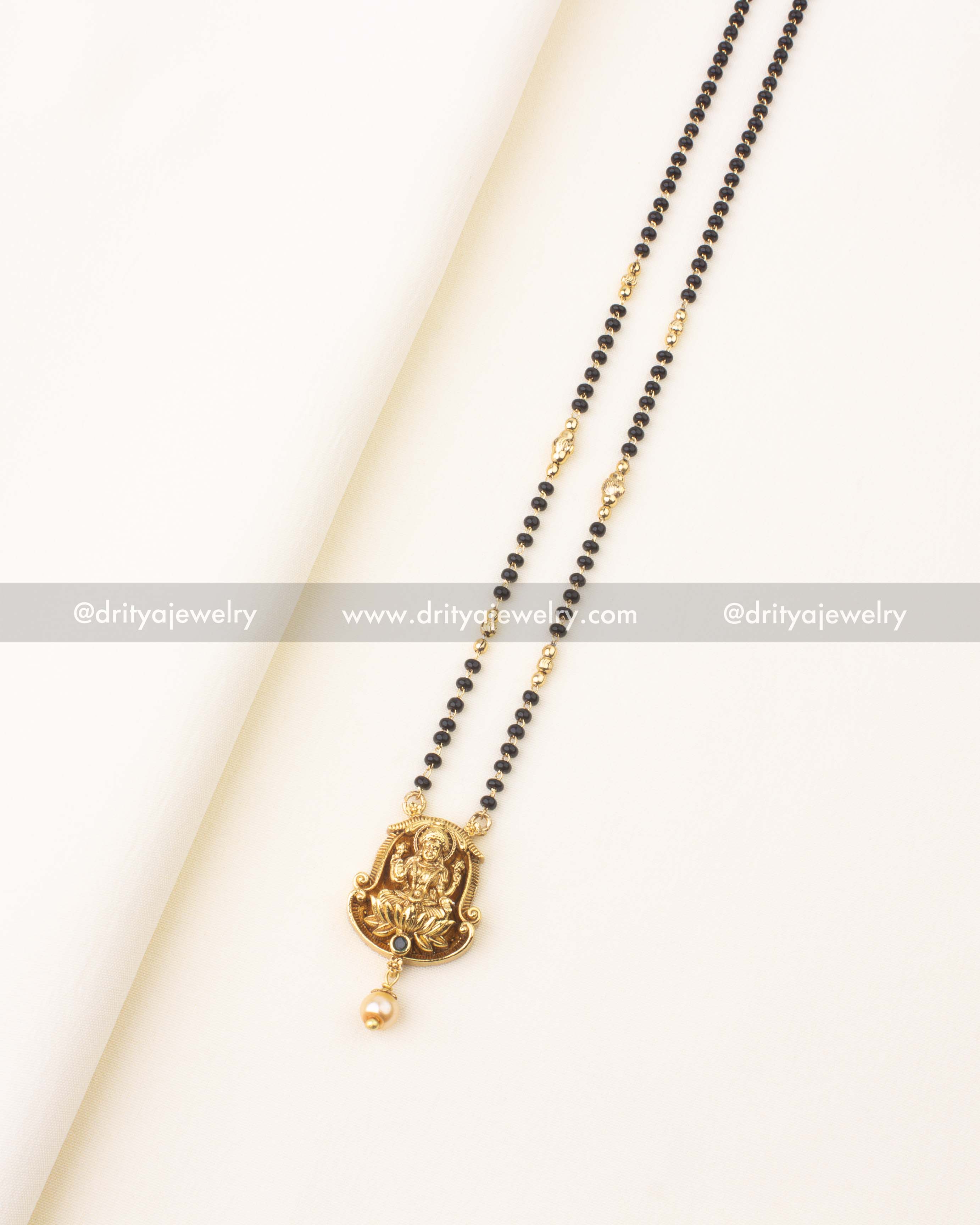 Double-line black beads necklace with temple-style Lakshmi pendant and pearl drop.