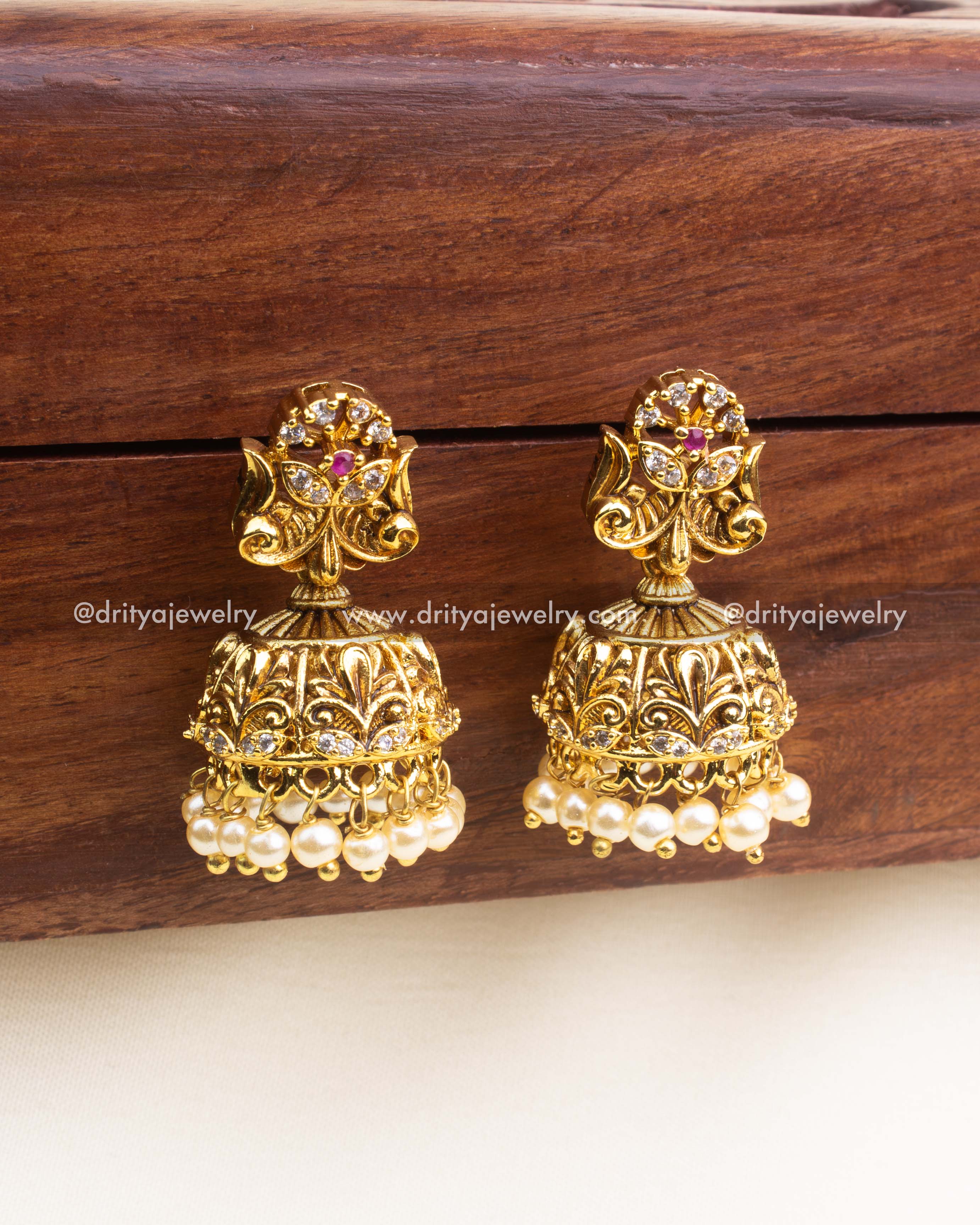 Traditional gold replica jhumka earrings with filigree design and pearl hangings by Dritya Jewelry.