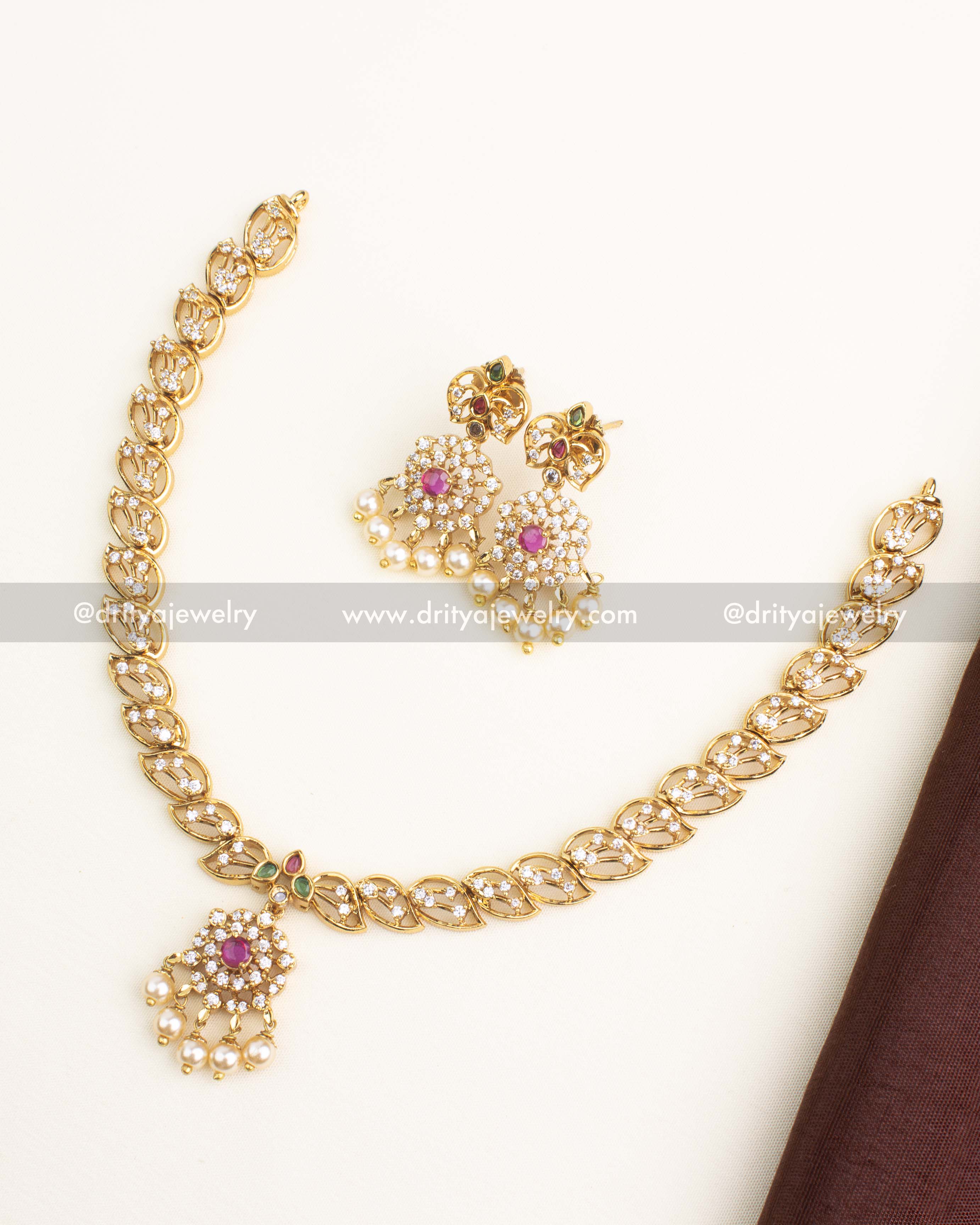 Gold replica short necklace set with CZ leaf motifs, ruby center pendant, pearls, and matching earrings.