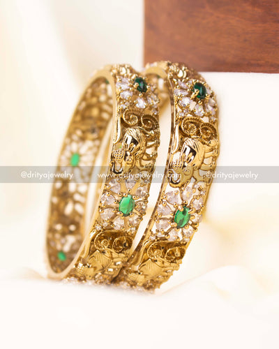 Pair of gold-finish bangles with elephant motif and floral CZ patterning.