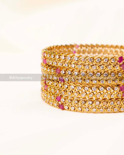Set of gold-plated CZ bangles with tear-drop stones and pink accents.