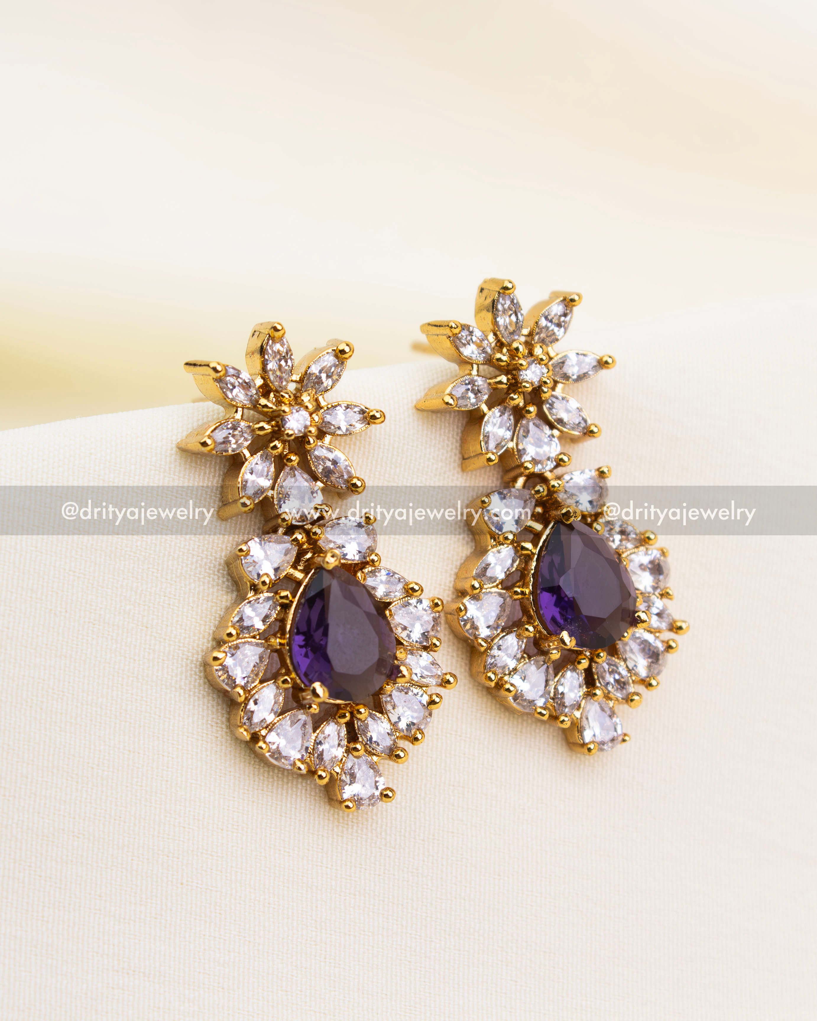Elegant gold earrings with violet stones and clustered CZ design.