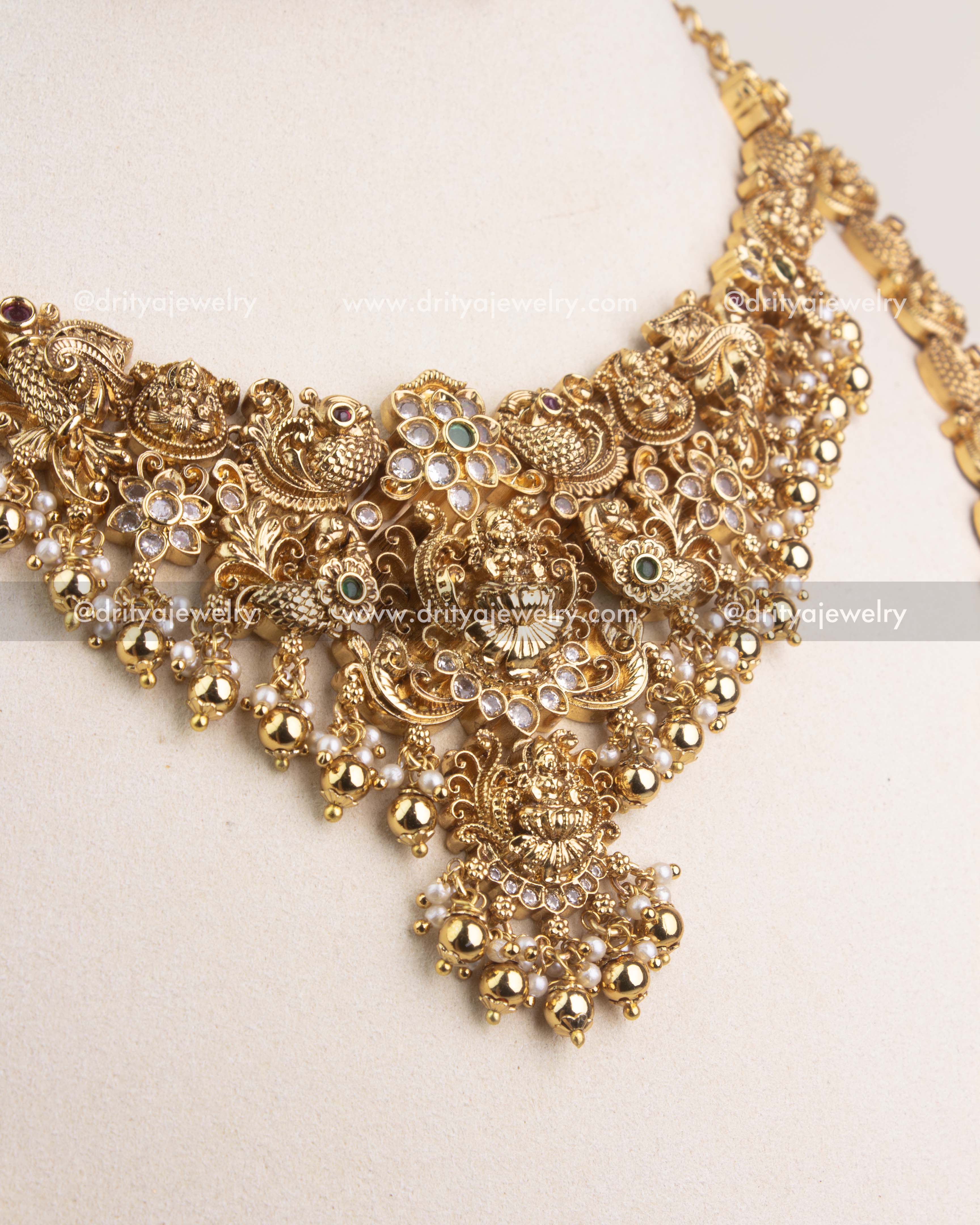 Close-up of antique gold temple necklace with goddess Lakshmi motif, peacocks, and bead hangings.