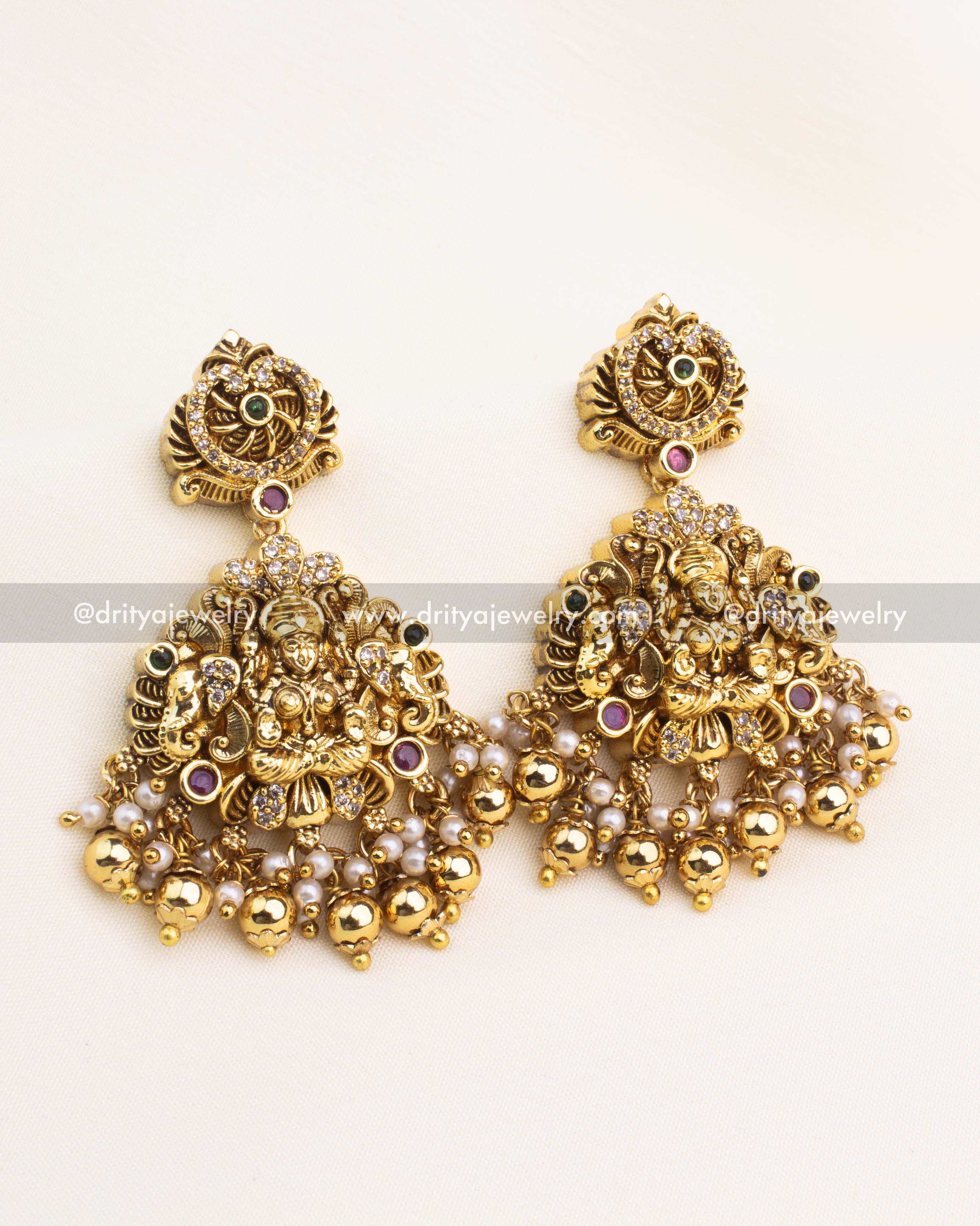 Matching temple dangler earrings with Lakshmi motif, AD stones, pearl clusters, and gold ball drops in antique temple finish.