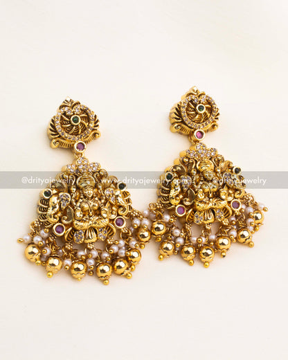 Matching temple dangler earrings with Lakshmi motif, AD stones, pearl clusters, and gold ball drops in antique temple finish.