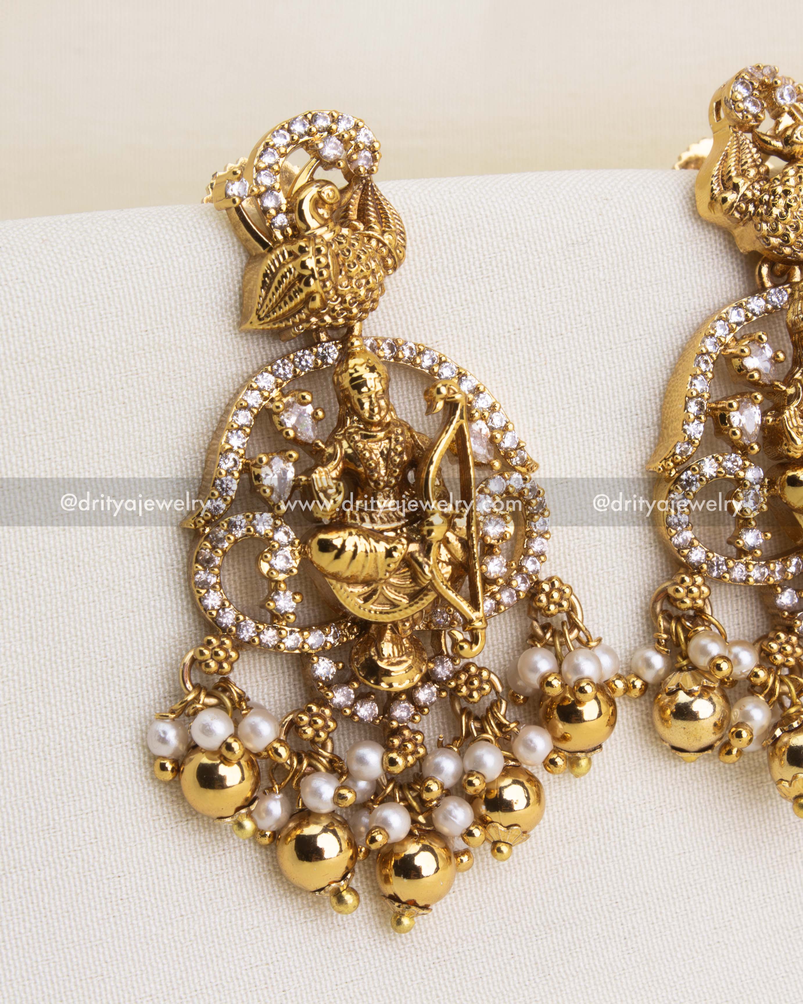 Temple-style dangler earrings with deity design, CZ accents, and golden bead drops.