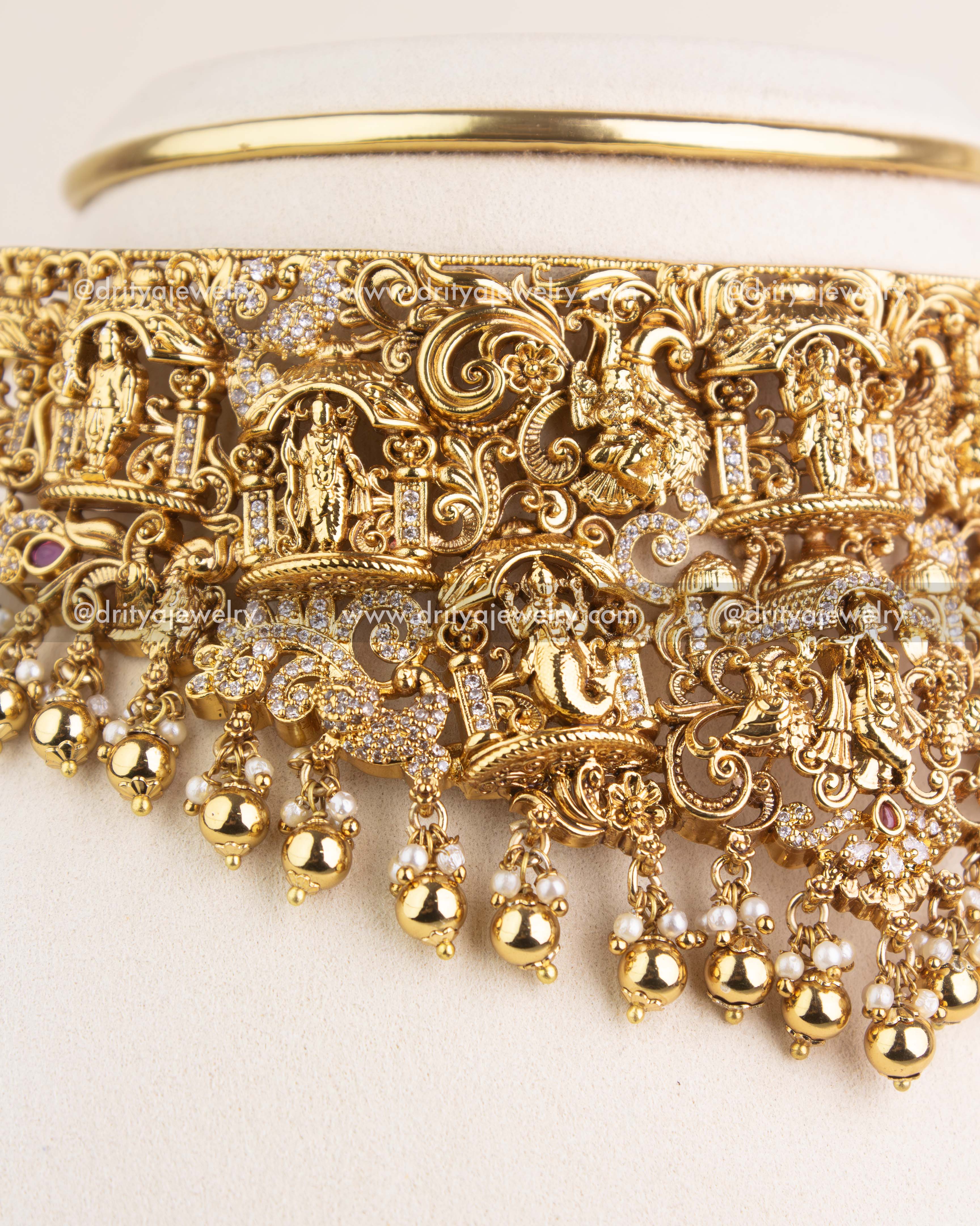 Intricate Nakshi carvings with divine figurines and golden finish on choker necklace.