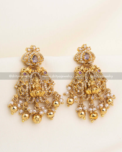 Pair of temple earrings with Lakshmi motif, purple CZ stones, and pearl-gold drops.