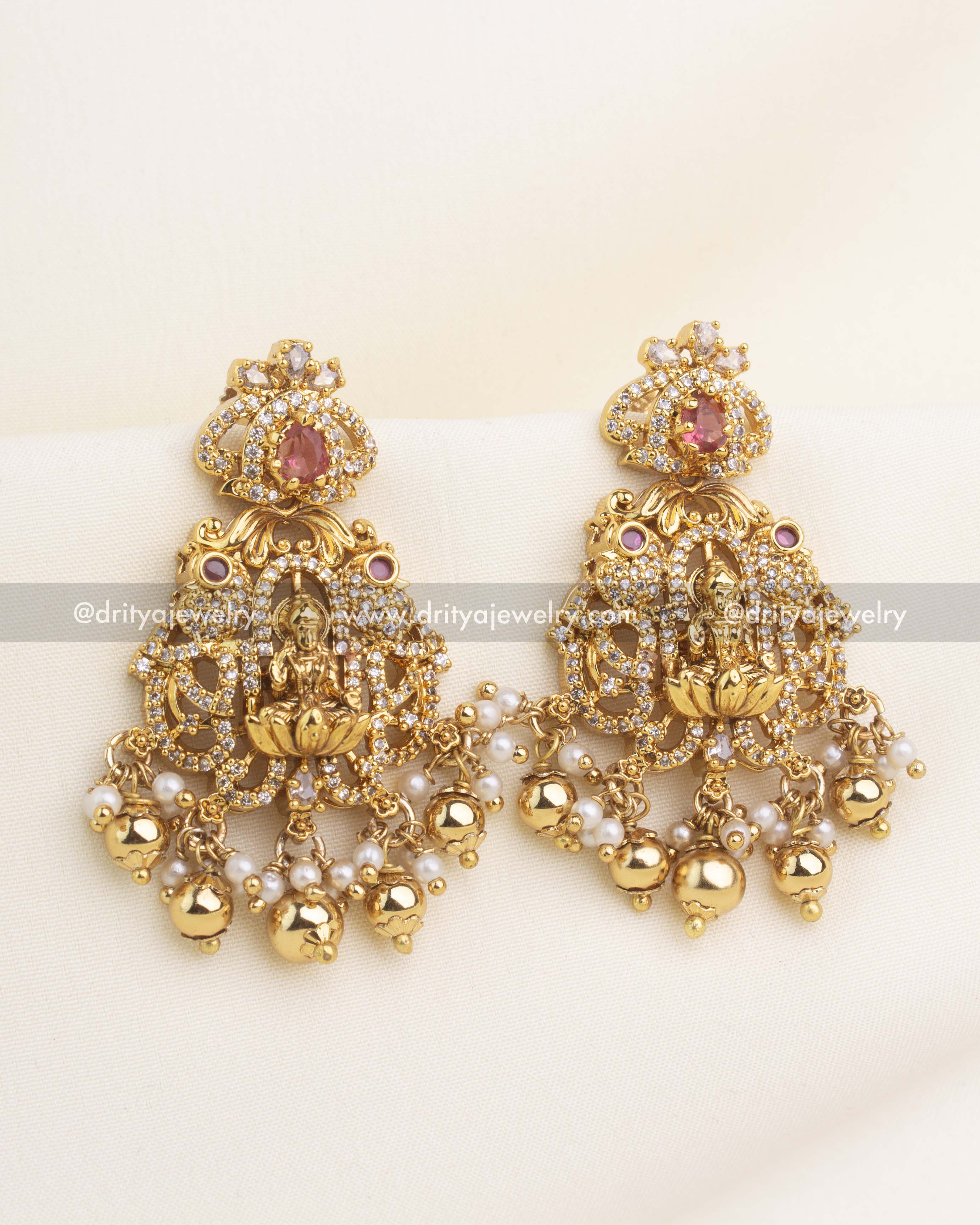 Red stone temple earrings with CZ sparkle, Lakshmi motif, and pearl-gold hanging droplets.