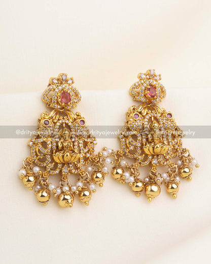 Red stone temple earrings with CZ sparkle, Lakshmi motif, and pearl-gold hanging droplets.