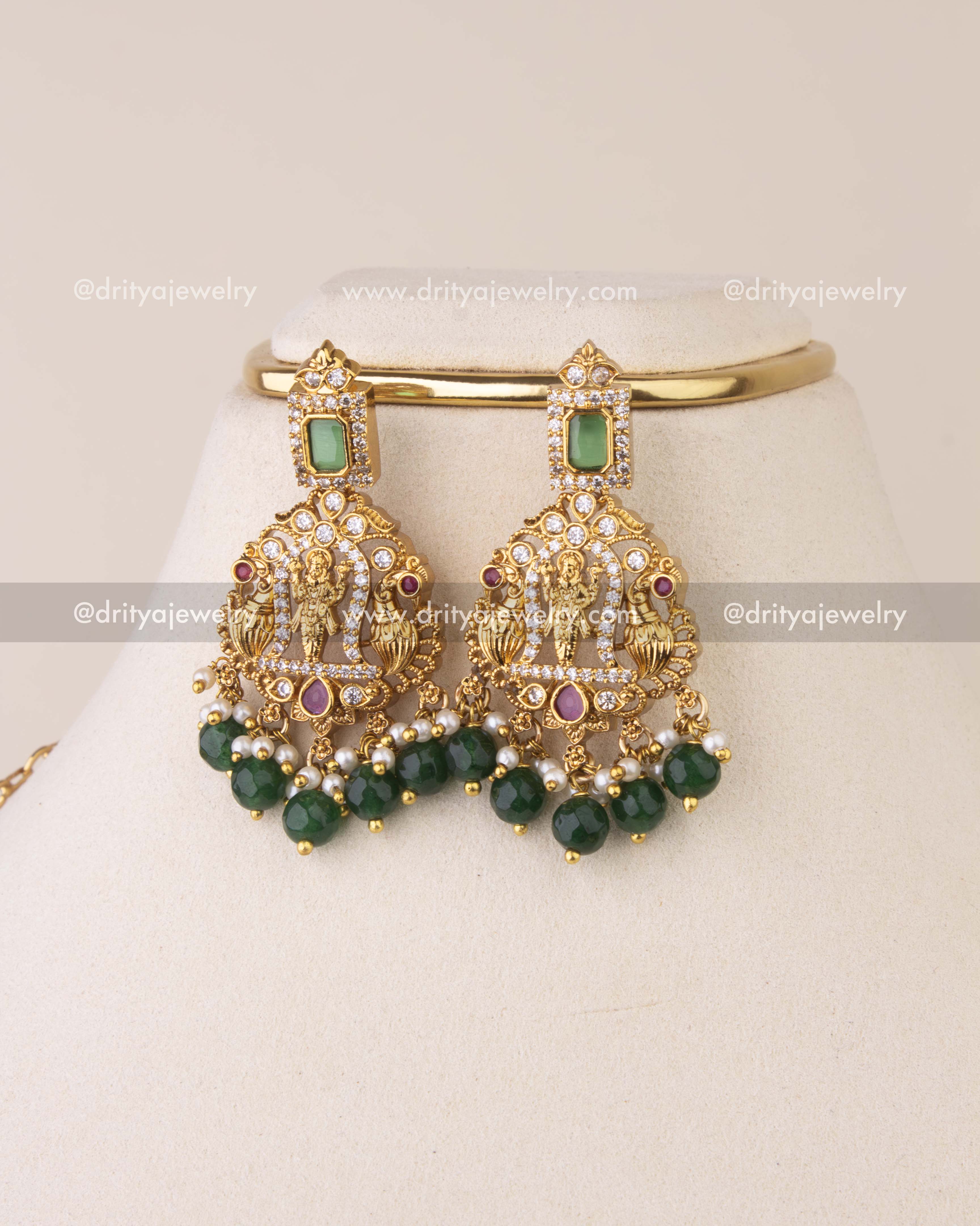Matching temple earrings featuring goddess motifs, emerald highlights, ruby accents, and green bead drops.