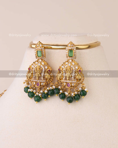Matching temple earrings featuring goddess motifs, emerald highlights, ruby accents, and green bead drops.