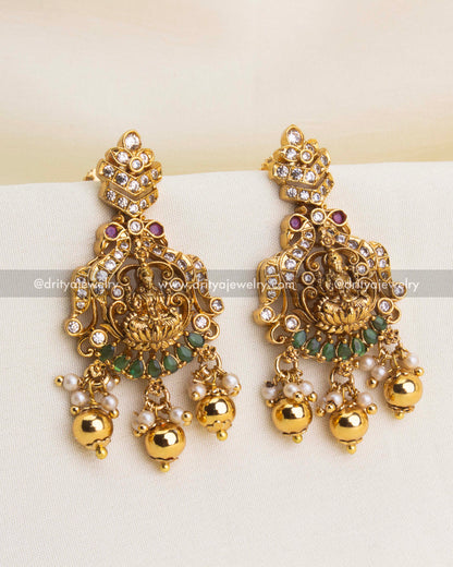 Traditional temple earrings with Lakshmi carving, CZ highlights, green stones, and pearl clusters.