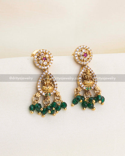 Matching Lakshmi earrings with CZ framing and dangling green bead drops in gold finish.