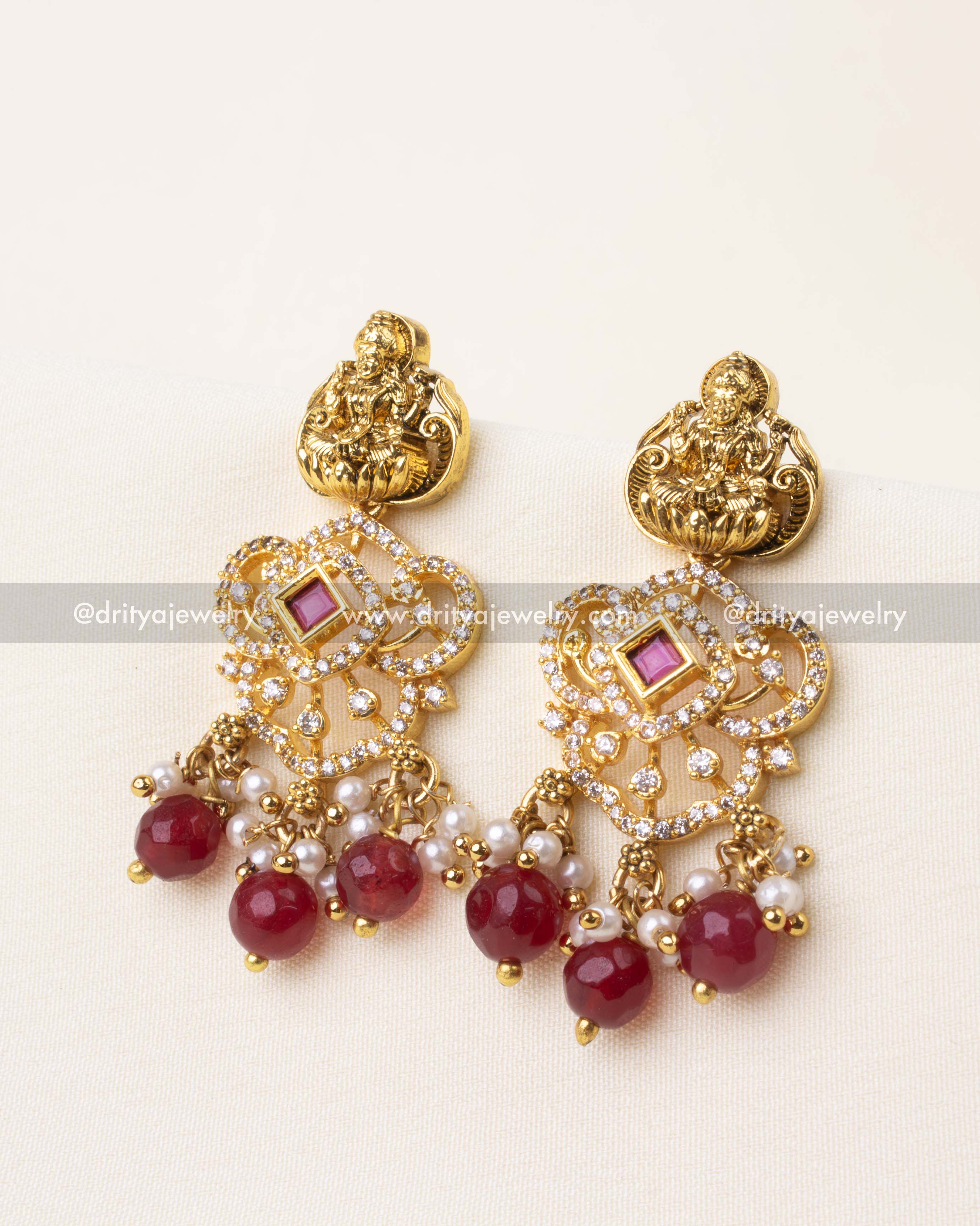 Ruby red drop earrings with temple motif, goddess Lakshmi, and antique gold finish.