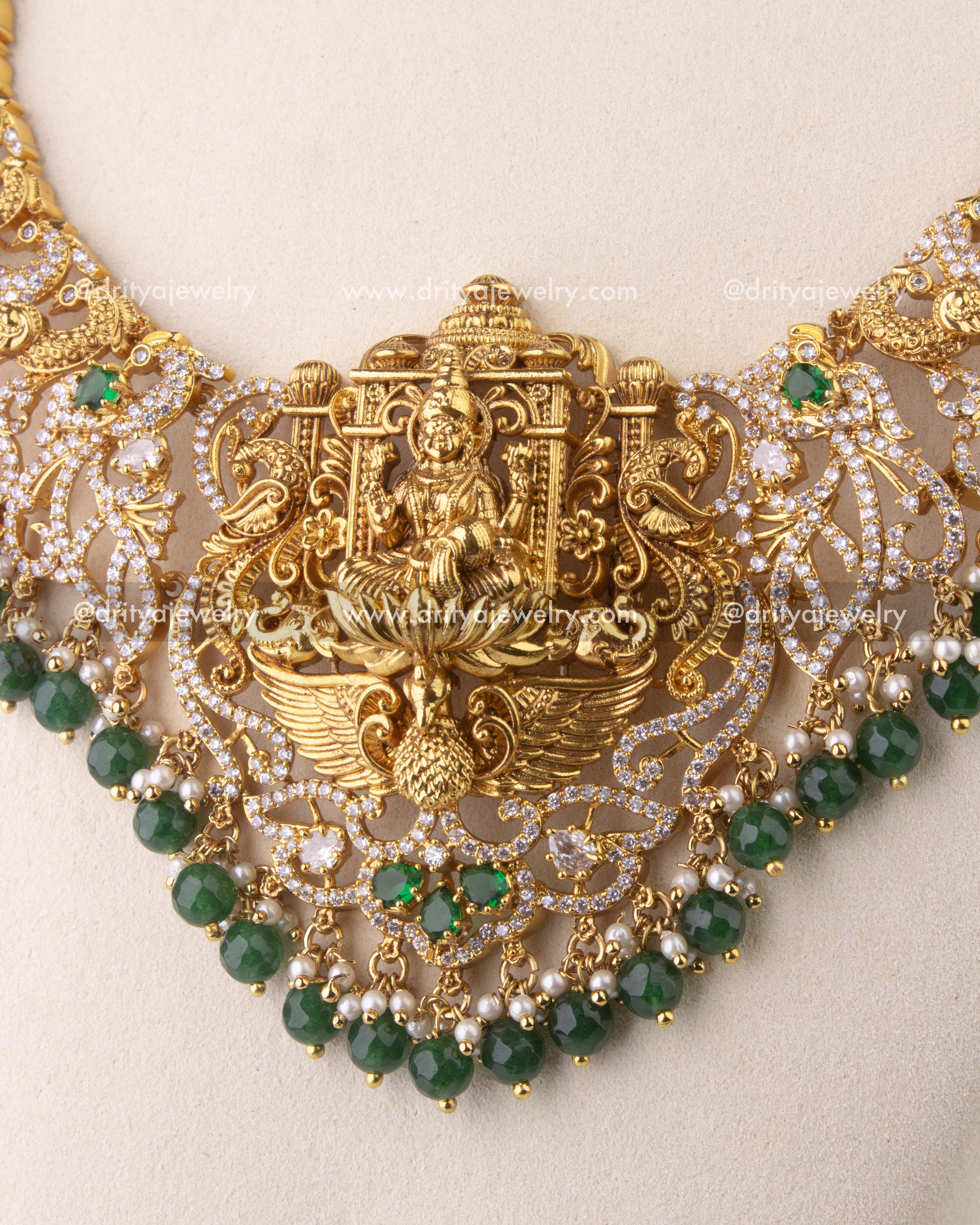 Close-up of Nakshi temple necklace with intricate peacock motifs and faceted green bead hangings.