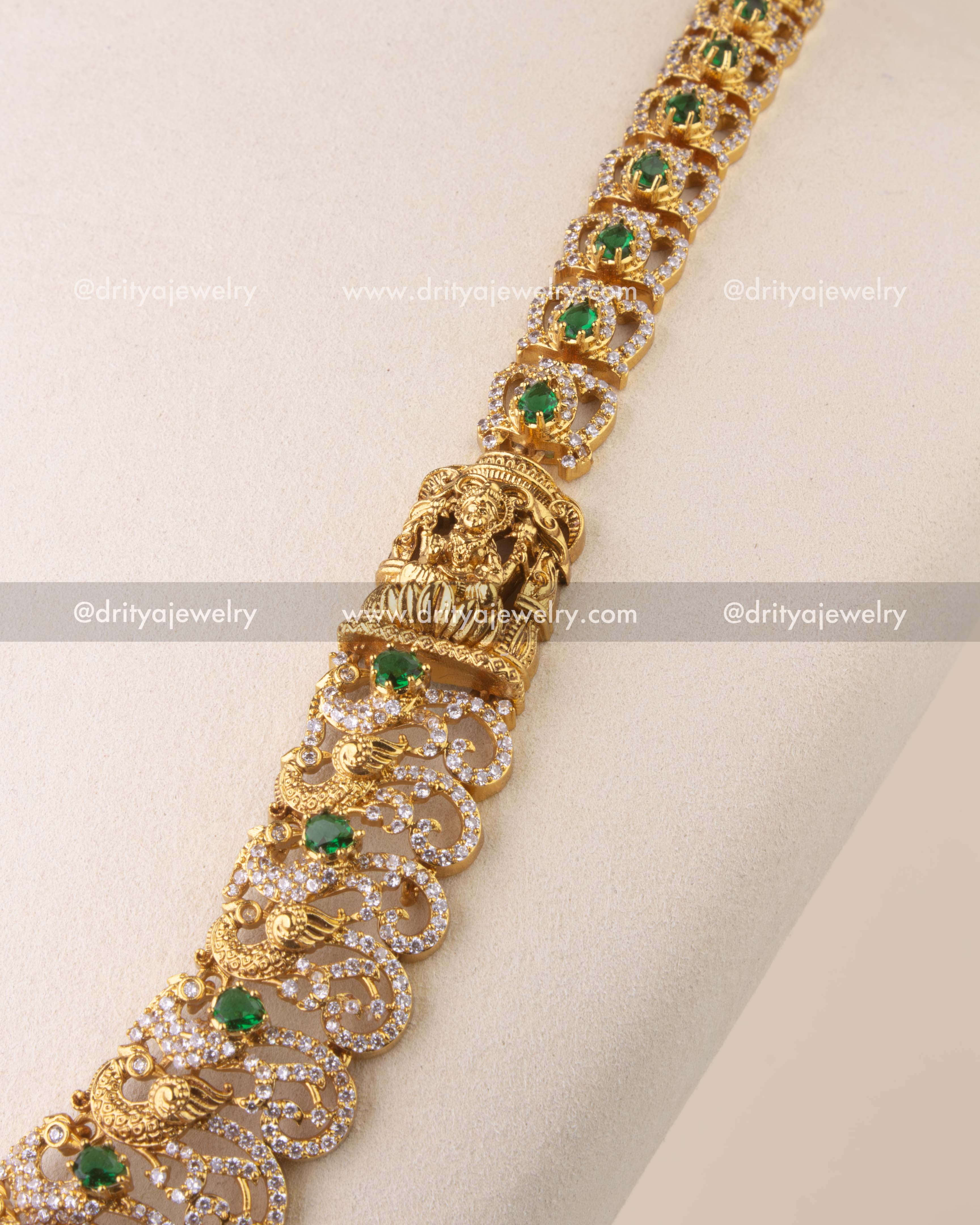 Close-up of Nakshi temple necklace with intricate peacock motifs and faceted green bead hangings.