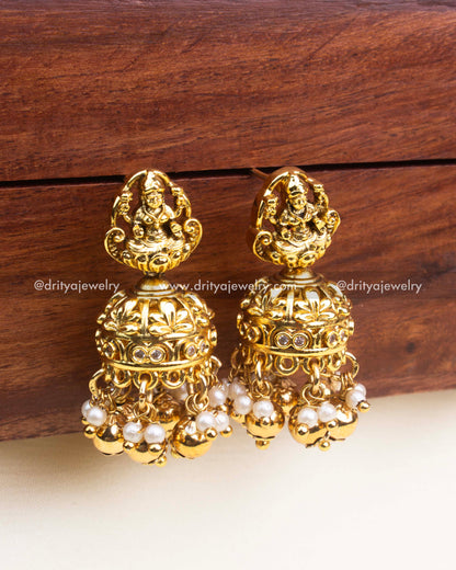 Antique gold jhumka earrings featuring Lakshmi motifs, pearls, and gold bead danglings.