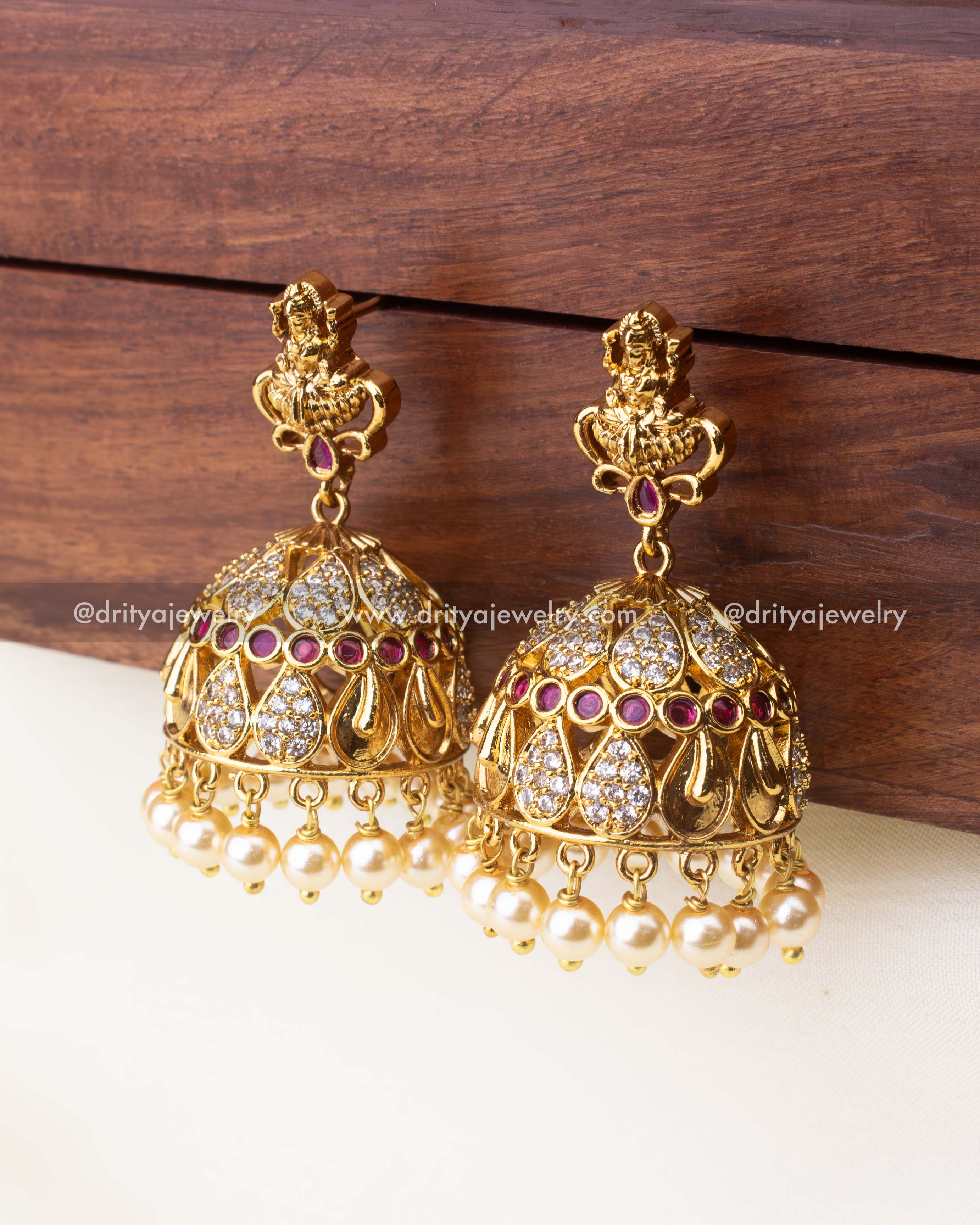 Intricate temple-style jhumka earrings with ruby accents, CZ detailing, and pearl hangings.