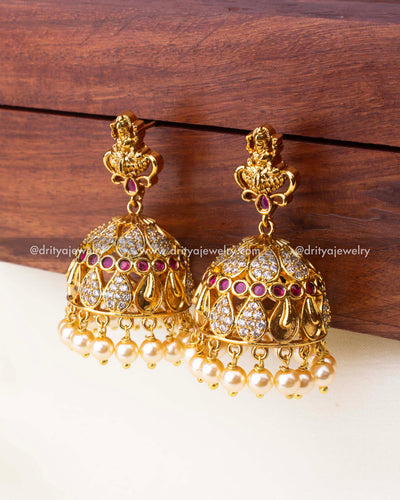Intricate temple-style jhumka earrings with ruby accents, CZ detailing, and pearl hangings.