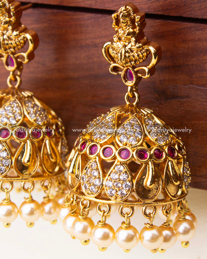 Intricate temple-style jhumka earrings with ruby accents, CZ detailing, and pearl hangings.