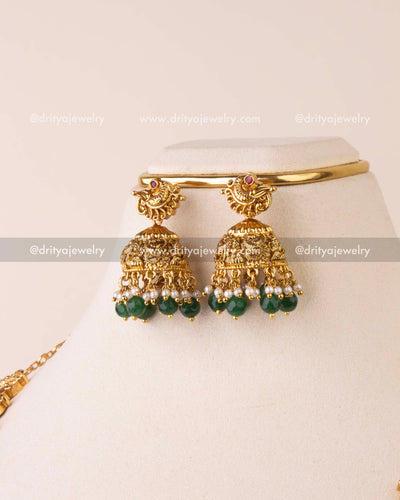 Traditional temple jhumka earrings with goddess motifs and green bead drops.