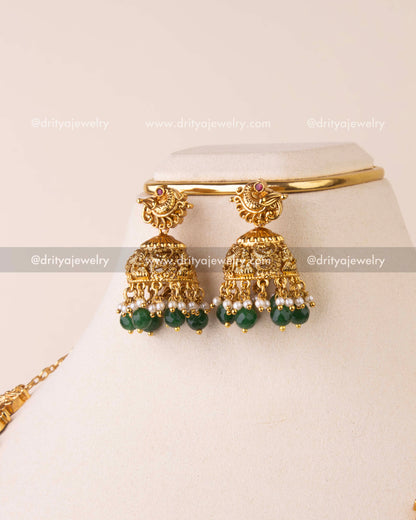 Traditional temple jhumka earrings with goddess motifs and green bead drops.
