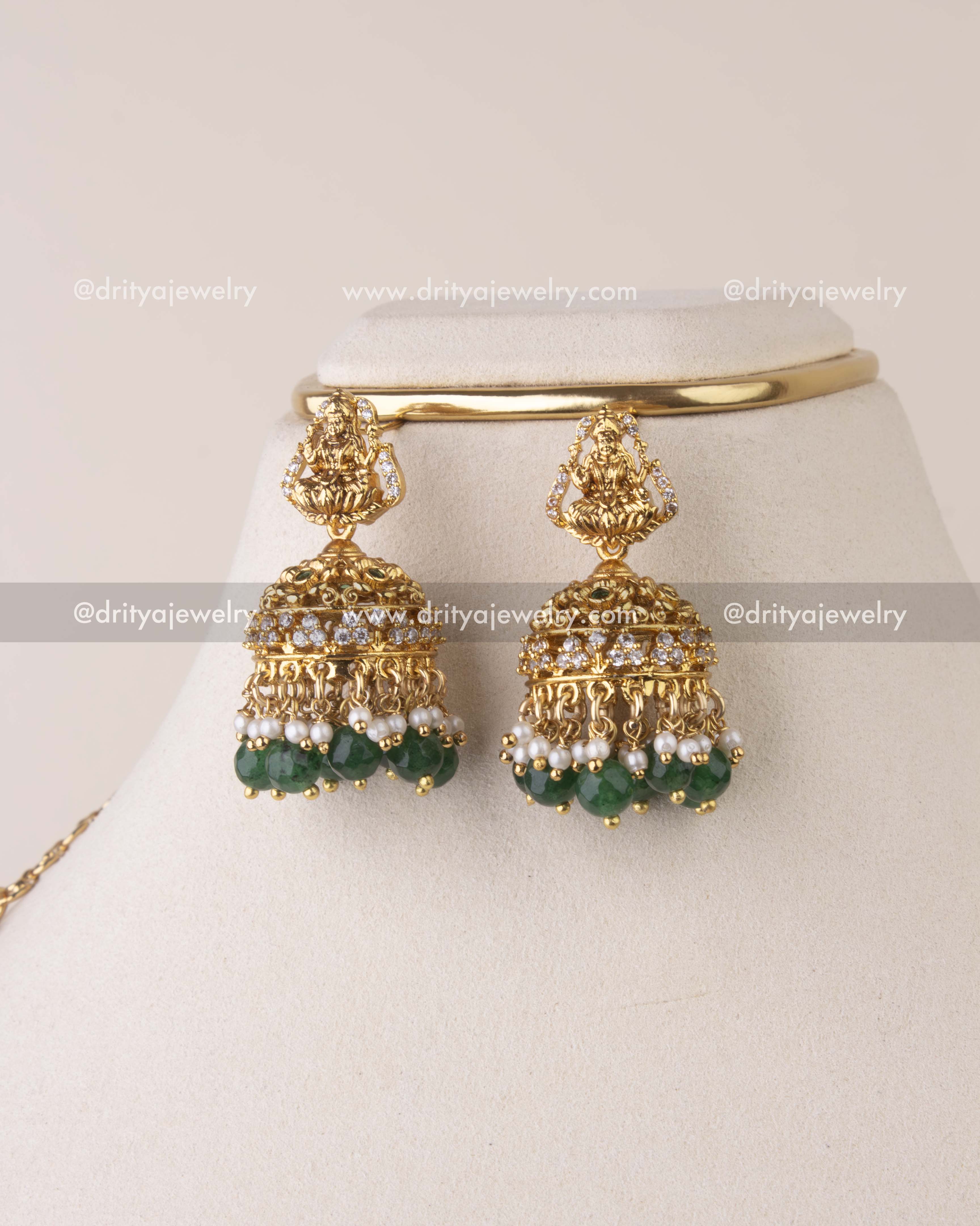 Matching temple jhumkas with Goddess Lakshmi motif, CZ stones, pearls, and green bead drops.