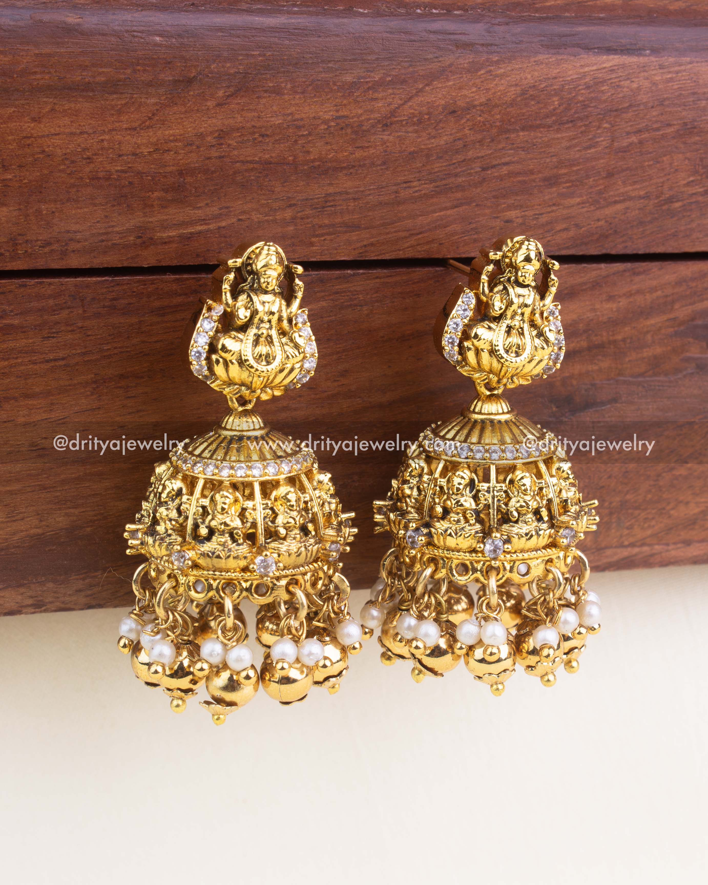 Lakshmi Nakshi jhumka earrings with CZ stones, pearl hangings, and antique gold finish.