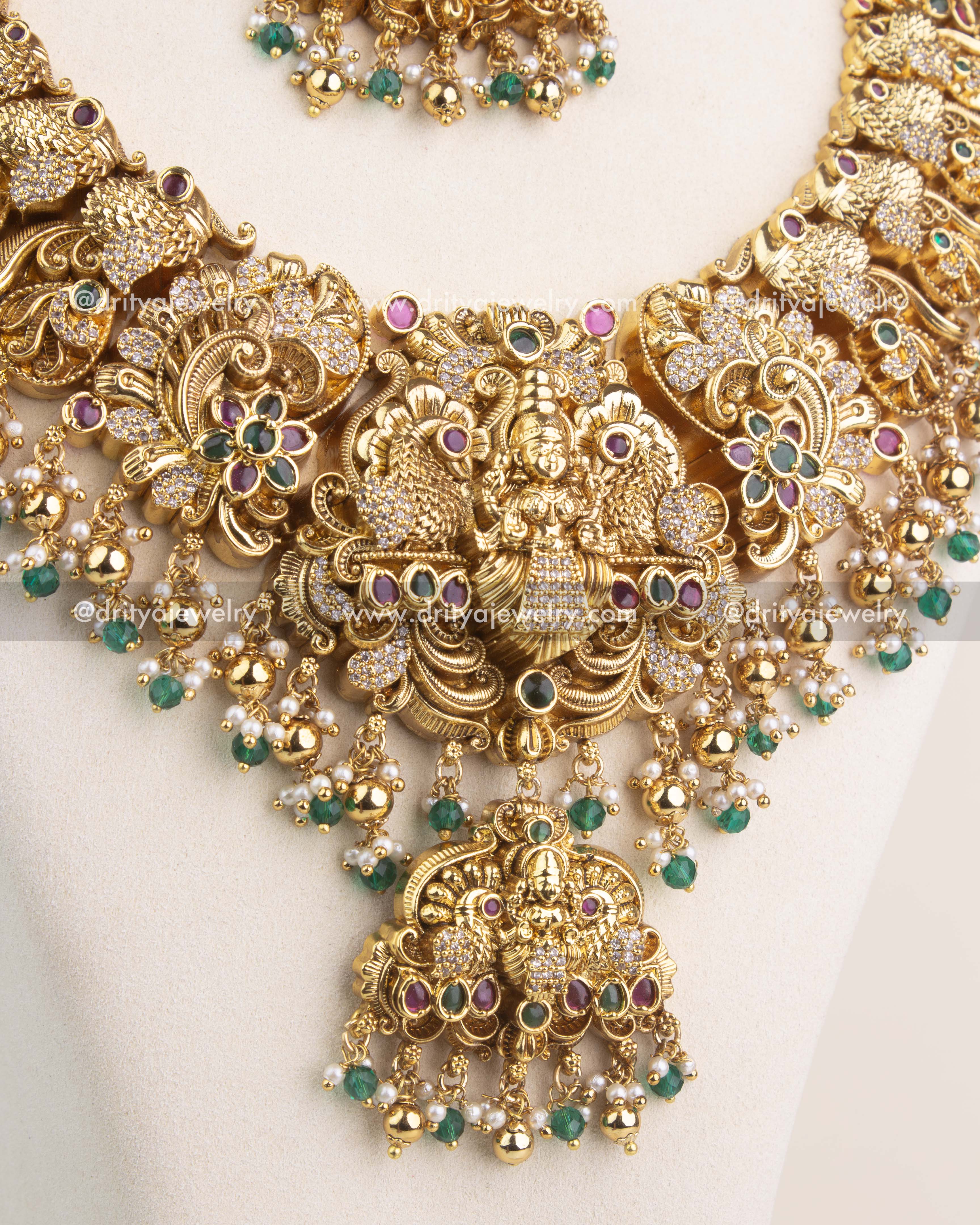 Close-up of temple long necklace with intricate Nakshi detailing, CZ stonework, and emerald green bead hangings.