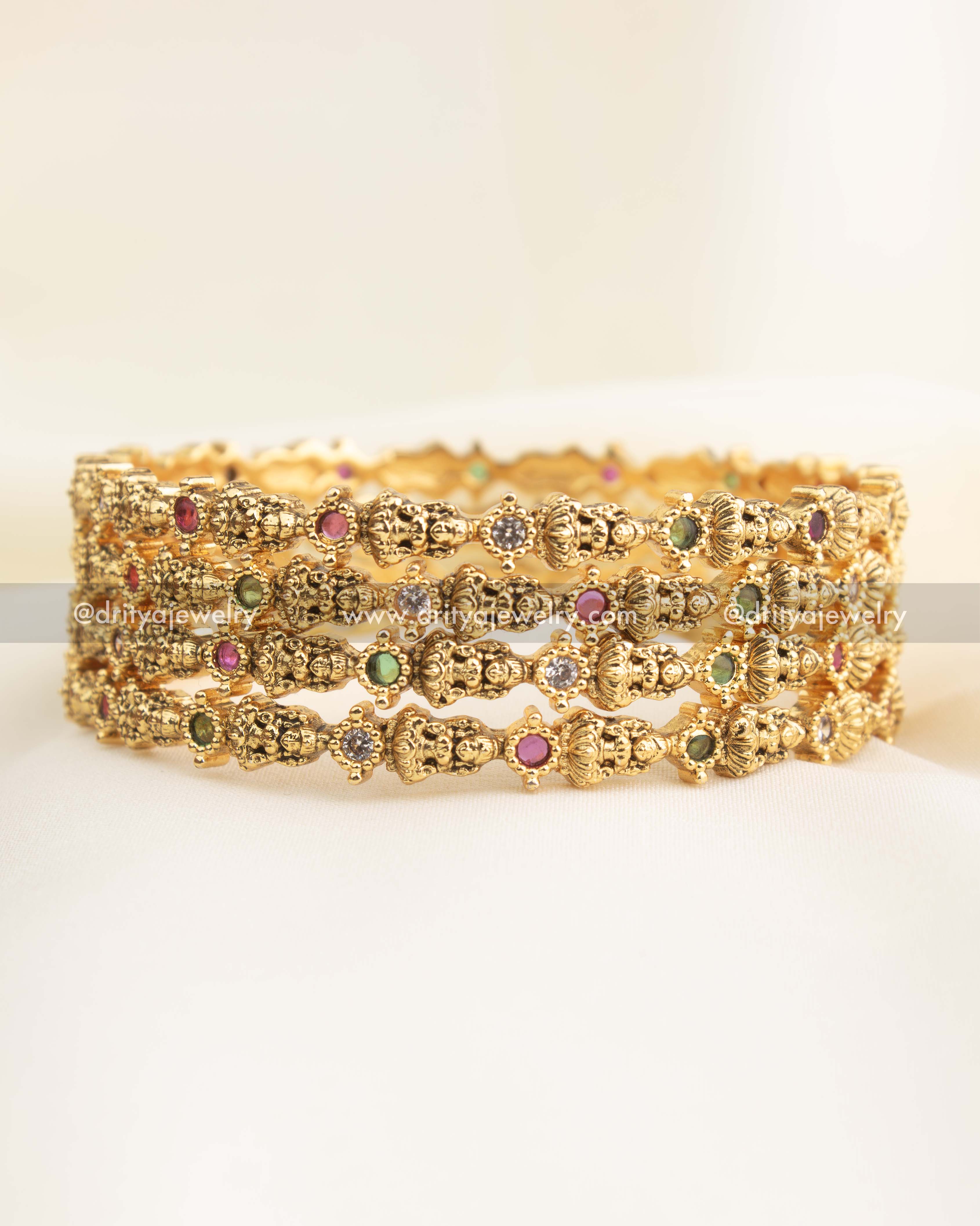 Antique gold temple bangle set featuring Lakshmi motifs and multi-coloured CZ stones.