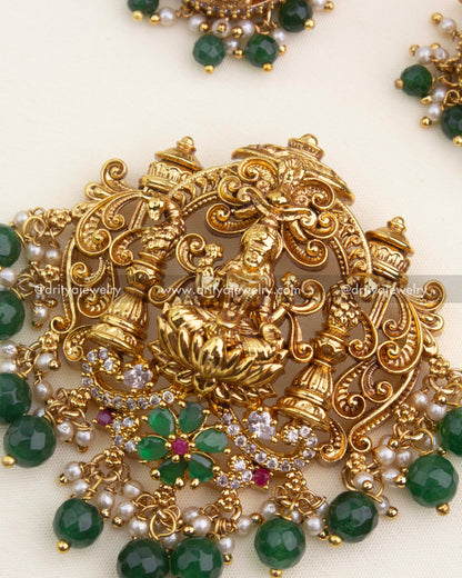 Intricate temple pendant featuring Goddess Lakshmi, pillars, CZ stones, green beads, and pearl clusters.