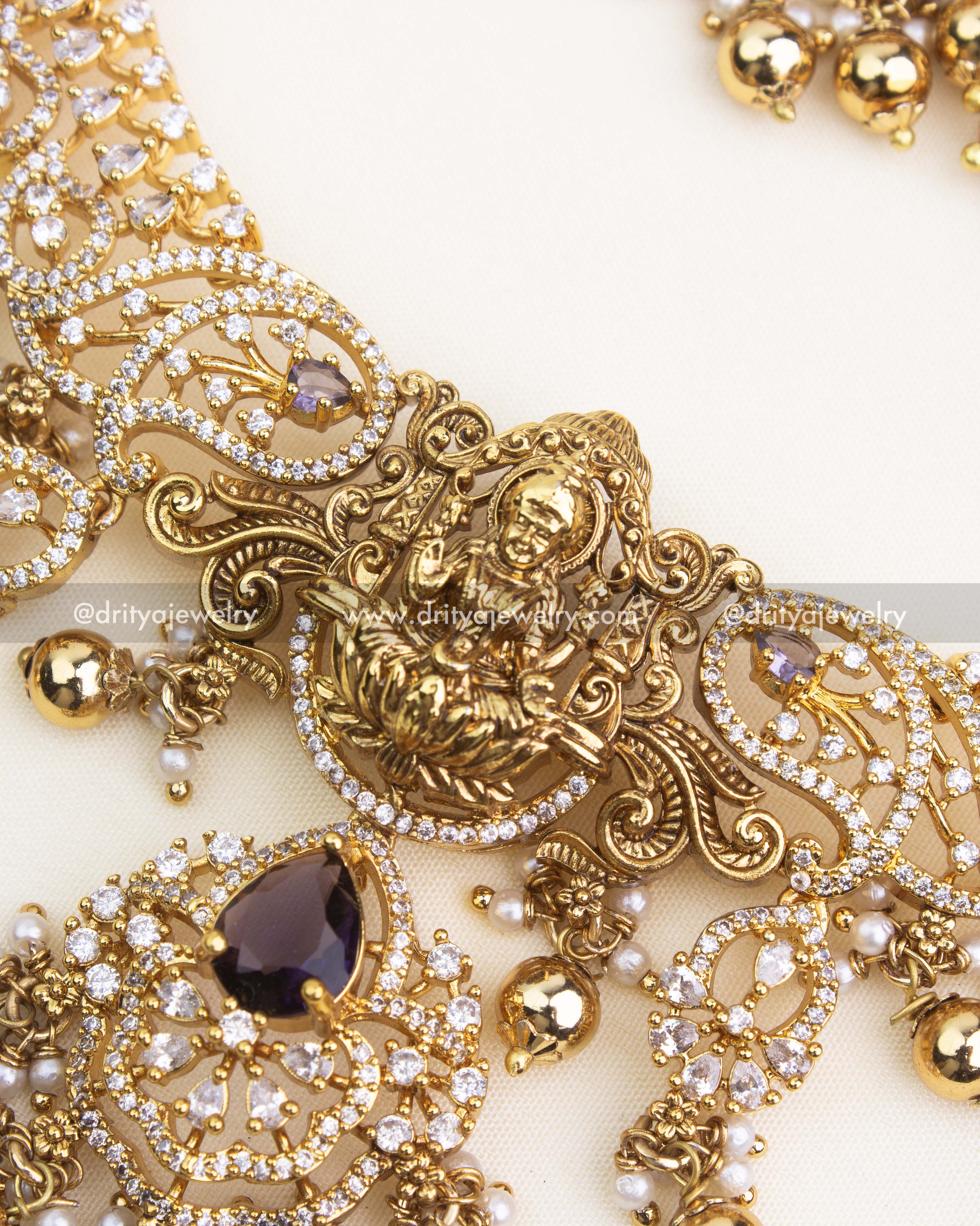 Intricate close-up of temple nakshi detailing and CZ work with purple teardrop stone.