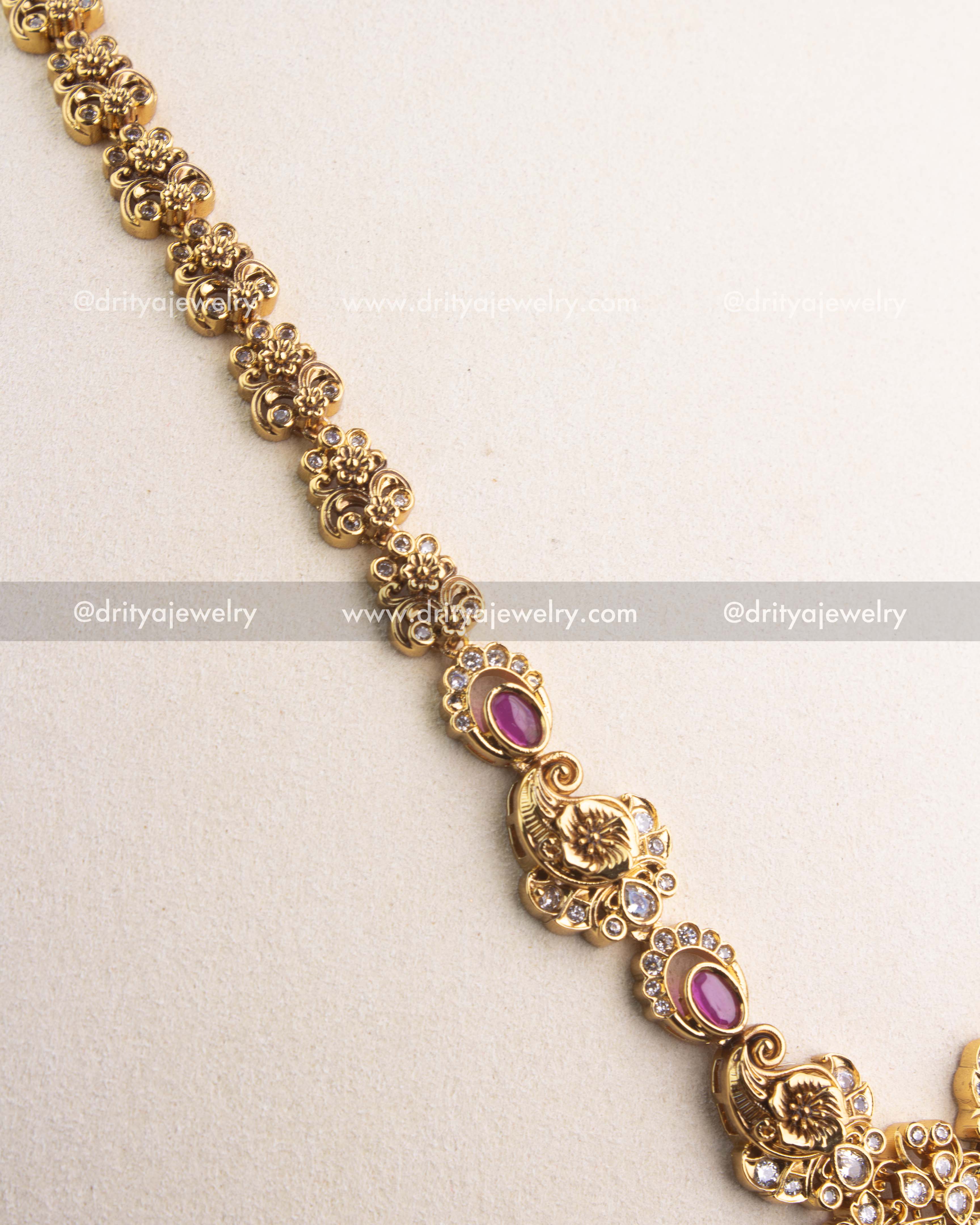 Close-up of gold-carved peacock motifs and ruby Kemp stones along the chain.