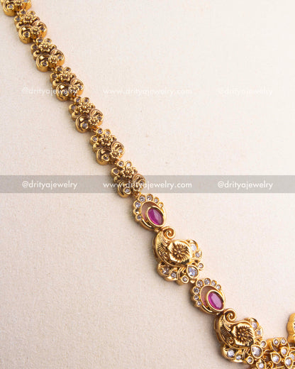 Close-up of gold-carved peacock motifs and ruby Kemp stones along the chain.