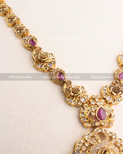 Close-up of gold-carved peacock motifs and ruby Kemp stones along the chain.