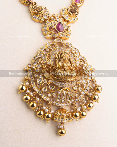 Intricate Lakshmi Devi pendant with CZ and ruby detailing in antique gold finish.