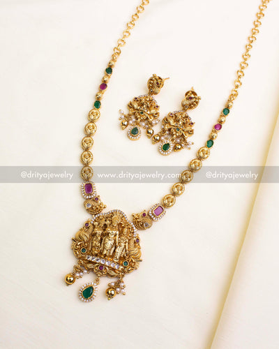 Antique gold temple necklace featuring Ram Parivar pendant, ruby-green stones, and pearl danglers.