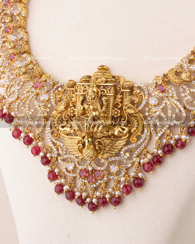 Close-up of Nakshi temple necklace with ruby red stones, peacock motifs, and antique gold finish.