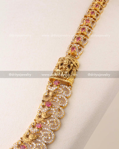 Close-up of Nakshi temple necklace with ruby red stones, peacock motifs, and antique gold finish.