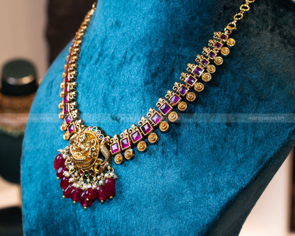 Side view of Dritya Jewelry’s temple necklace set, showcasing square-cut ruby stones and spiral gold motifs in an antique gold finish.