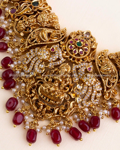 Zoomed-in view of goddess Lakshmi pendant with floral motifs and ruby red bead fringe on temple-style bridal necklace.