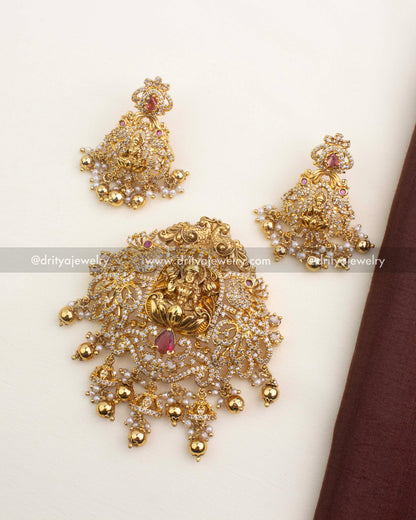 Traditional gold temple pendant set featuring Lakshmi, CZ stones, and a red centerpiece stone.