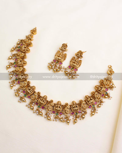Antique temple-style necklace with Lakshmi figures, floral design, pink-green accents, pearls, and gold balls.