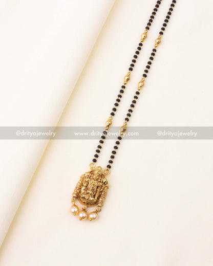 Elegant mangalsutra with glossy black beads, antique gold pendant of Lord Venkateswara Swamy, and pearl danglers.
