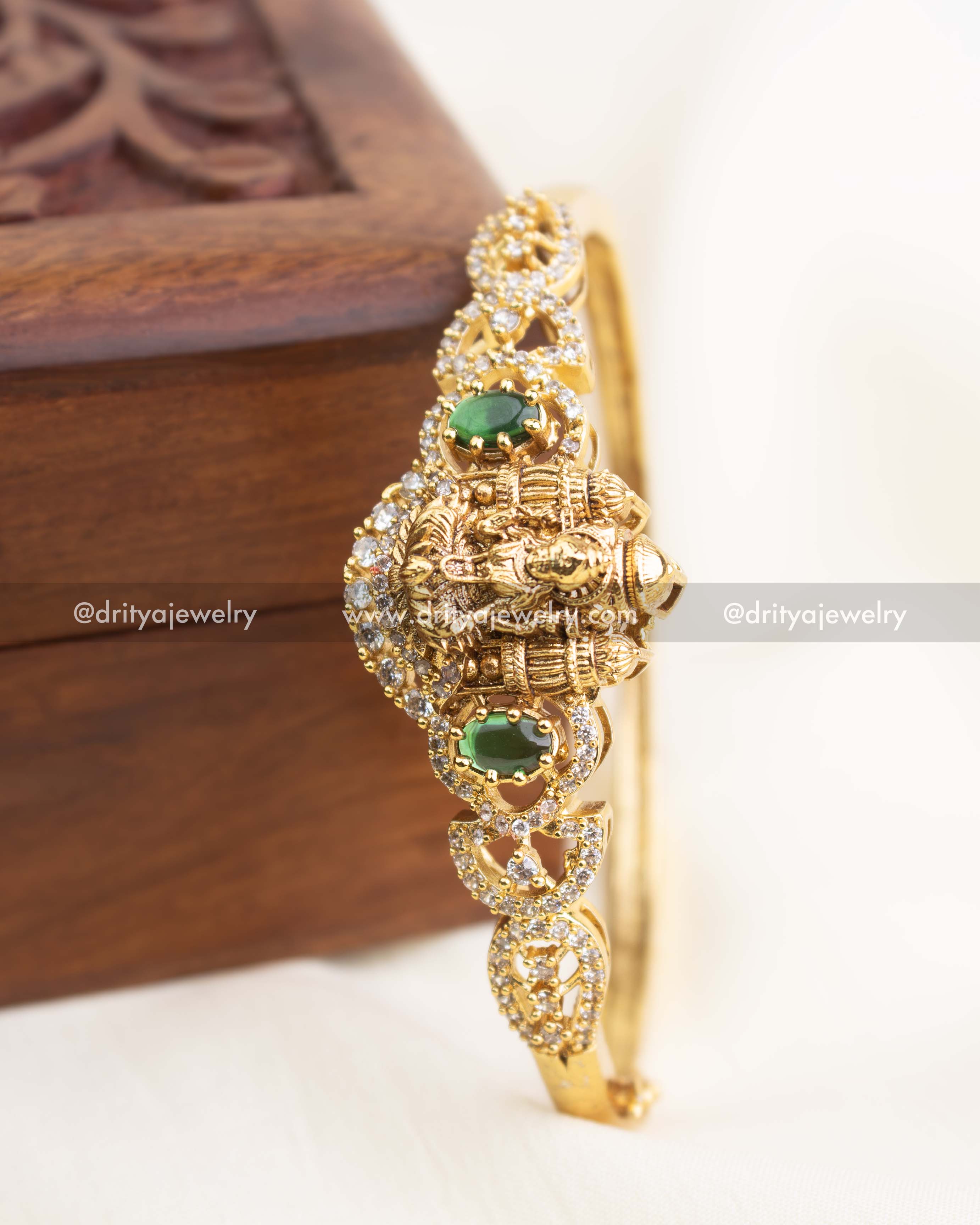 Side-angle view of temple kada featuring intricate nakshi carvings and green oval stones.