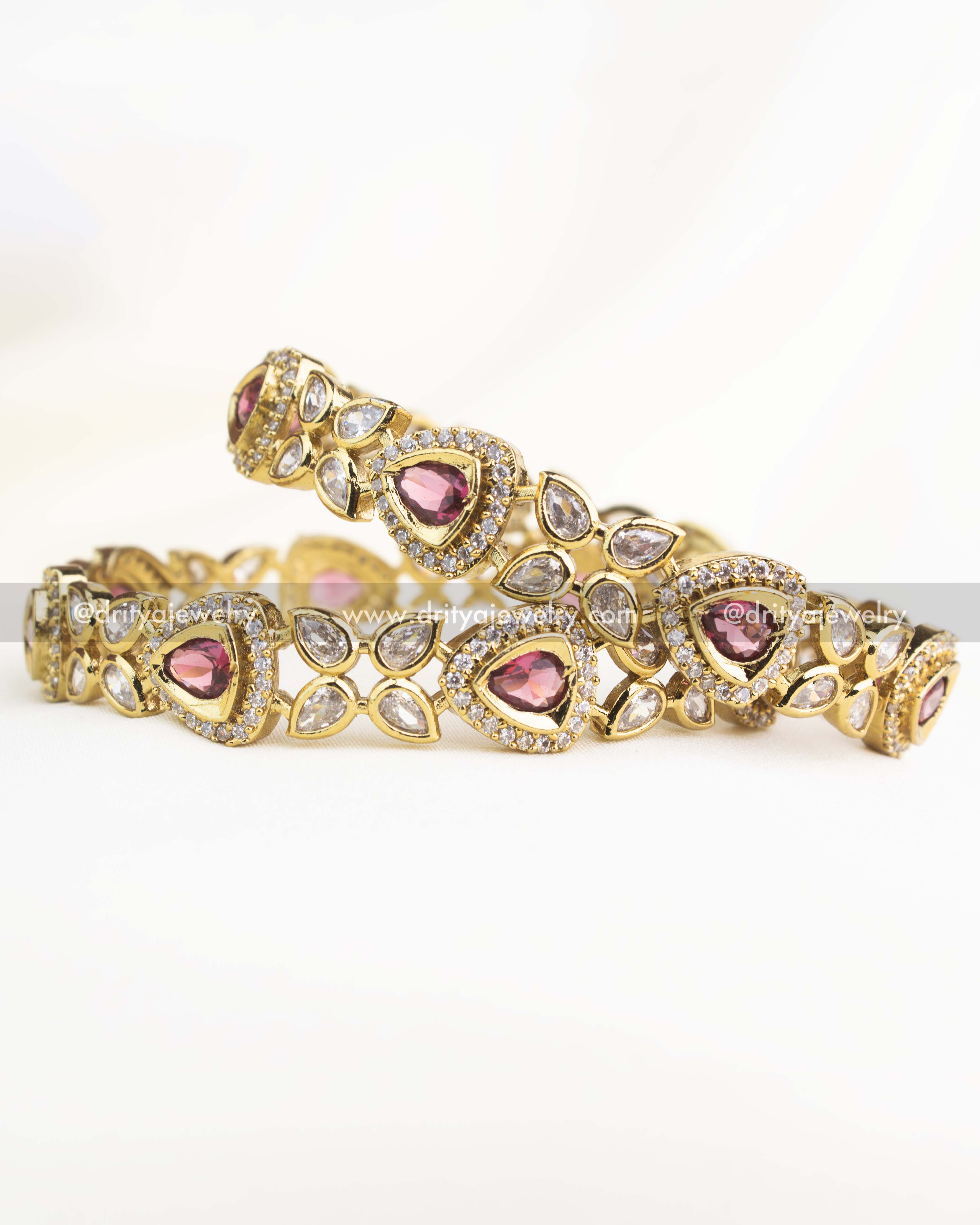 Victorian-style bangles with ruby red teardrop stones and white AD detailing in gold-plated finish.