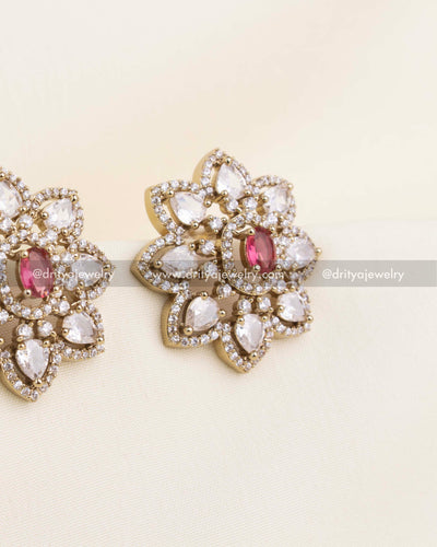 Close-up of floral CZ stud earrings featuring a ruby center stone and micro CZ border detailing