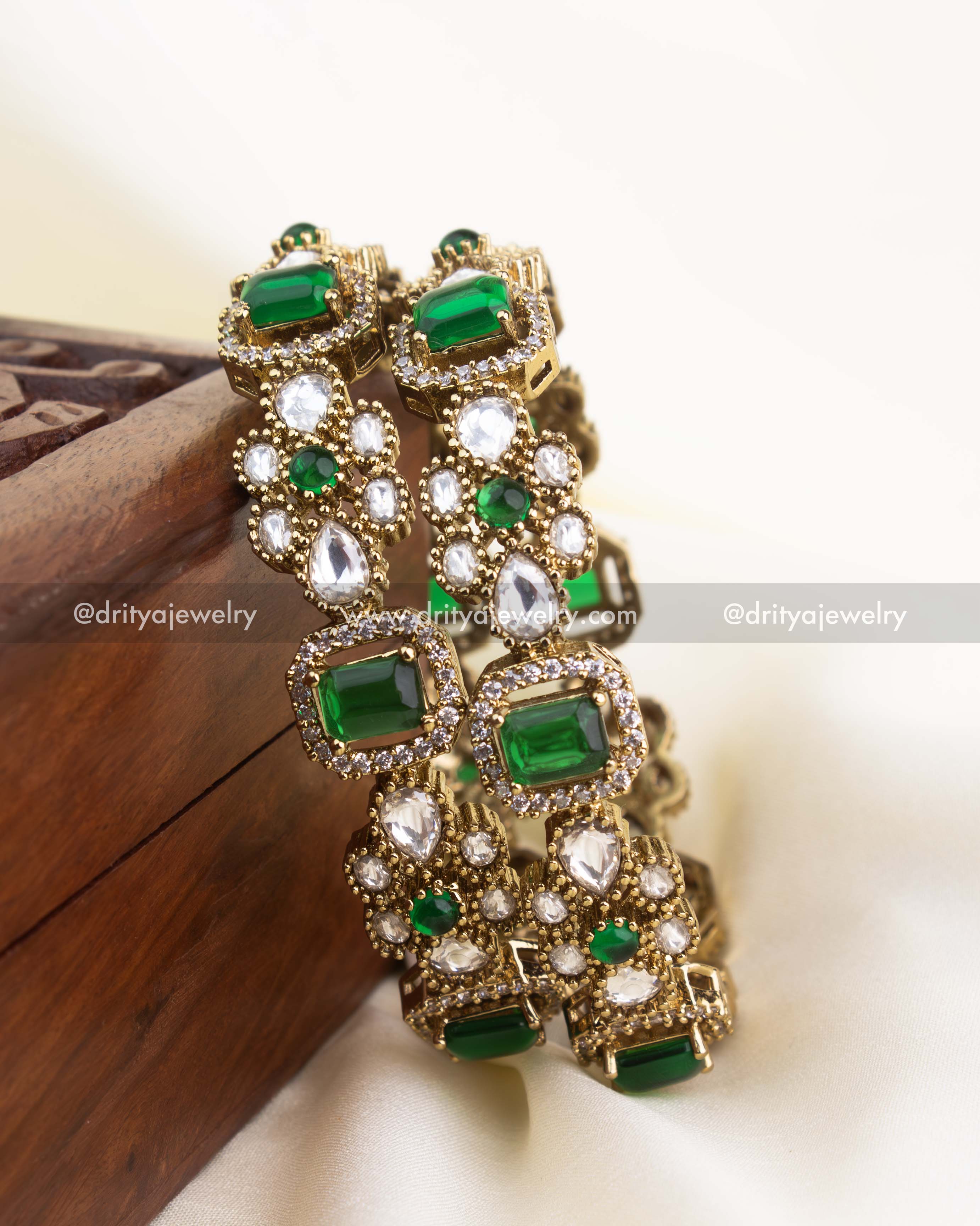 Handcrafted imitation bangles featuring emerald green stones, white polki kundan, and antique gold finish.